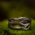 Indlæs billede i Gallery viewer, Et nærbillede af en rustik, sølvfarvet ring på en bund af grønt mos. Denne fingerring - Eryn Design - Moria (Simpel) har et organisk, sammenflettet design med uregelmæssige åbninger, hvilket giver den et naturligt og robust udseende. Baggrunden er sløret, hvilket understreger teksturen og detaljerne i dette stykke dansk design håndlavede smykker.