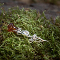 Indlæs billede i Gallery viewer, Broche Rose med Rav 925s Sølv, en sølvfarvet broche formet som en stilk med blade, holder autentisk rav, der ligner en blomsterknop, og hviler på levende grønt mos. Det detaljerede håndværk af denne romantiske gave efterligner en naturlig rose.