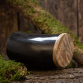 Indlæs billede i Gallery viewer, En poleret sort Drikkeglas Horn Plain (500ml) med en glat træbund hviler på en rustik overflade omgivet af grønt og træbark. Baggrunden af træplanker fremhæver den naturlige og jordiske stemning.
