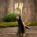 Indlæs billede i Gallery viewer, Drikkehorn Yggdrasil U. Mønster, med et indviklet Yggdrasil-design, står stolt oprejst på endnu et drikkehorn mod en rustik træbaggrund. Grønt i kulissen tilføjer et naturligt touch til denne vikingemarkedsinspirerede scene.