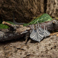 Indlæs billede i Gallery viewer, En detaljeret, bådformet metallisk broche i 925s Sterling sølv hviler på et groft stykke bark. Det indviklede design fanger lyset og viser dets håndværk. Grønt løv i den slørede baggrund tilføjer et naturligt touch til scenen.
